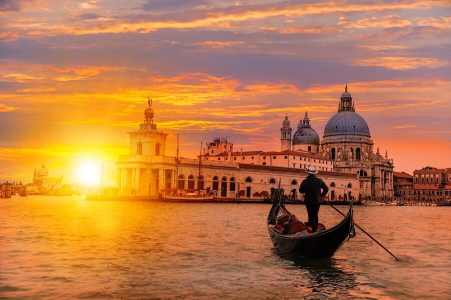 A gondola on the water at dusk with the Salute behind it, Venice
